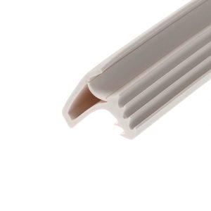 Close-up of a white plastic object with curved edge and multiple parallel grooves or slots, photographed at an angle.
