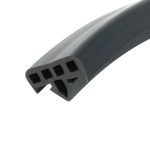 Close-up of a black plastic component with rectangular square-shaped openings along its curved surface, photographed diagonally.