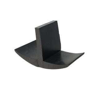 Black, boomerang-shaped wooden object with a curved blade resting on a flat surface; close-up view.