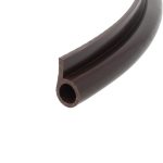 Close-up of a curved dark chocolate piece with a square cross-section and a hollow circular channel at the end.