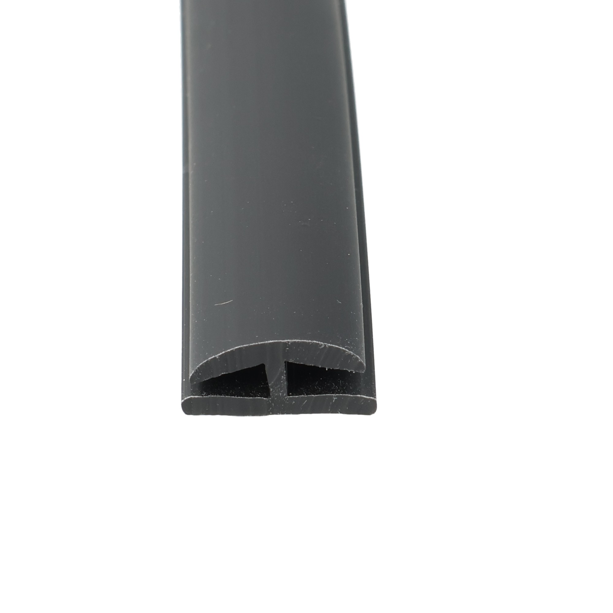uszczelka-krawedziowa-do-szyby-plyty-poliweglanowej-miekkie-pvc-typ-h-3-x-12-x-14mm-czarna-12-321-01-3 - Centrum uszczelek Close-up of a dark gray plastic object with a curved bottom and two rectangular cutouts at the lower edge.