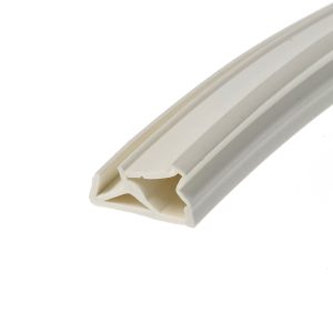 Close-up of a white plastic extrusion with hollow channels and beveled edges, photographed at a diagonal angle