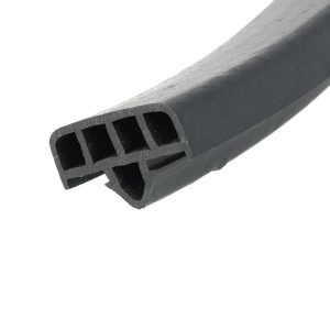 Close-up of a dark gray cylindrical object with square cutouts along its side, showing a scratched, textured surface.