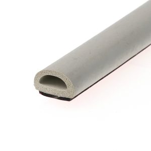 Close-up of a porous foam ring resting on a diagonal gray surface with a pink edge in the background.