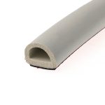 Close-up of a light gray foam pipe insulation curled into a circular ring on a pale surface.