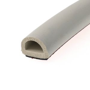 Close-up of a light gray foam pipe insulation curled into a circular ring on a pale surface.