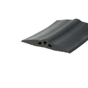 Close-up of a dark grey roof tile with a curved edge and round holes along the bottom edge, photographed at an angle.